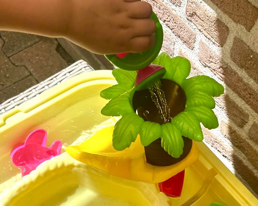 Gieter met water in de tuin van de opvang